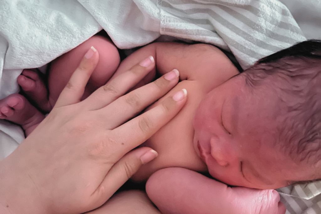 Mother's hand on newborn daughter while sitting in lap